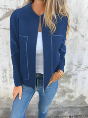 Giacca blu donna, zip frontale, indossata con jeans e top bianco. Moda casual autunnale, stile elegante e moderno.