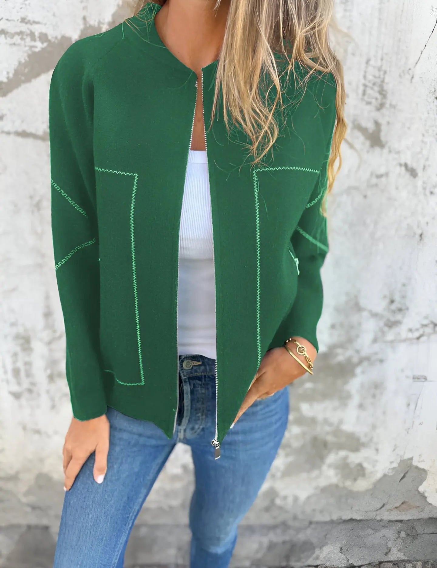 Giacca verde donna, stile casual, con cuciture a contrasto, indossata su top bianco e jeans. Moda autunnale, abbigliamento femminile trendy.