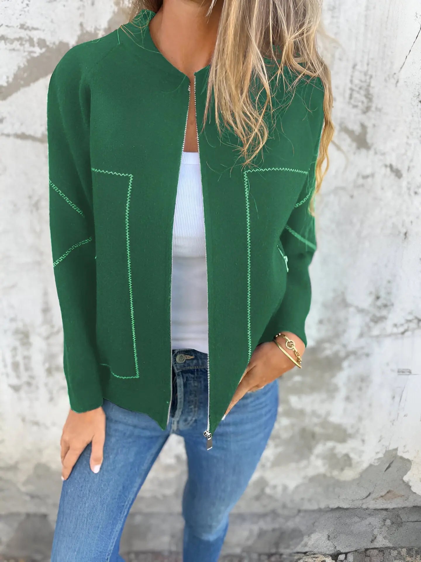 Giacca verde donna, stile casual, con cuciture a contrasto, indossata su top bianco e jeans. Moda autunnale, abbigliamento femminile trendy.