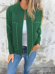 Giacca verde donna, stile casual, con cuciture a contrasto, indossata su top bianco e jeans. Moda autunnale, abbigliamento femminile trendy.