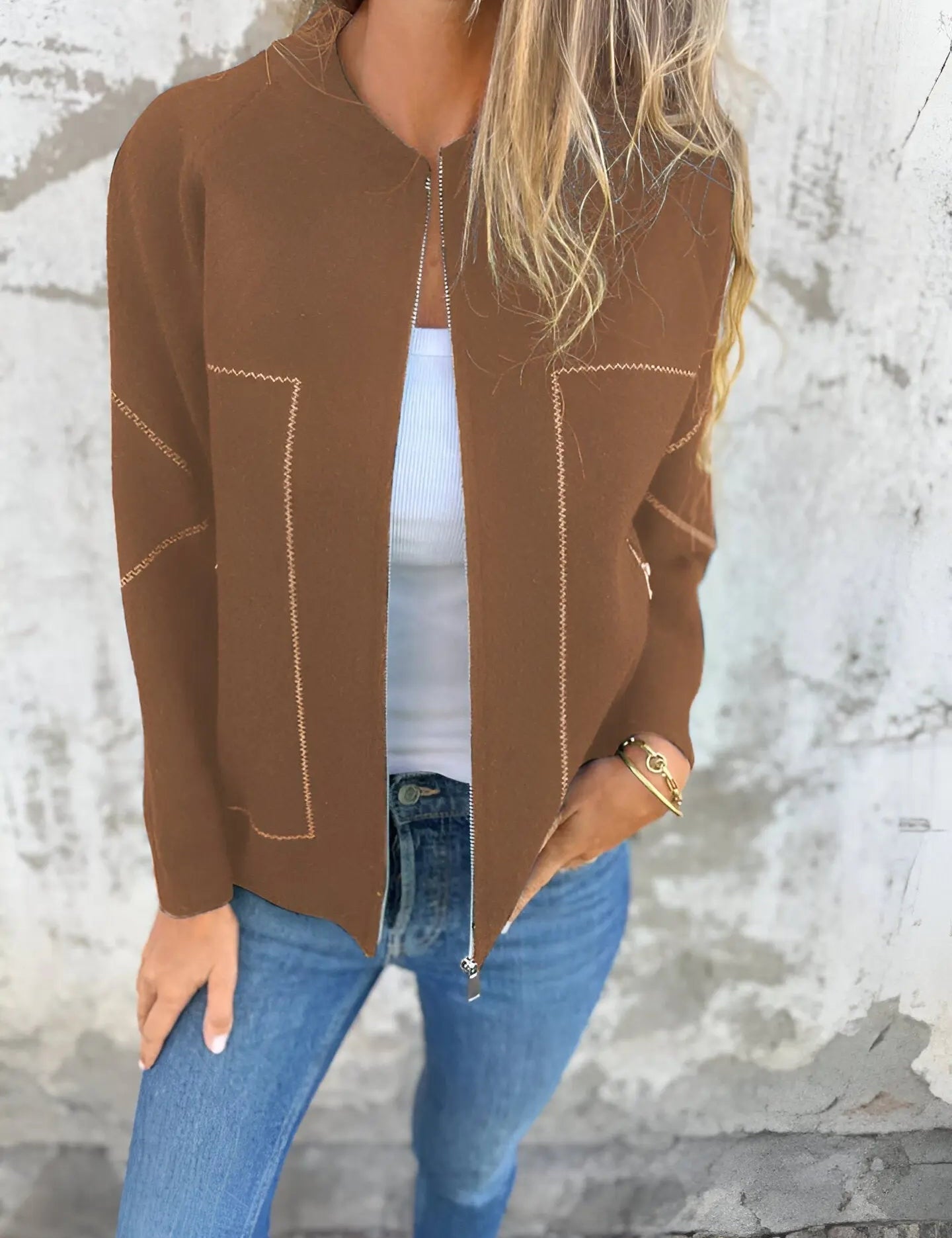 Giacca marrone da donna con zip, indossata su top bianco e jeans blu. Look casual chic, moda autunnale, abbigliamento femminile elegante.