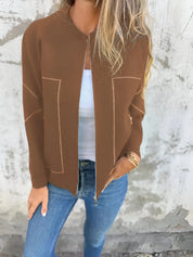 Giacca marrone da donna con zip, indossata su top bianco e jeans blu. Look casual chic, moda autunnale, abbigliamento femminile elegante.