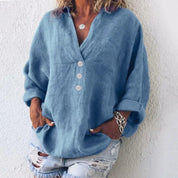 Camicia donna in lino blu, maniche lunghe, bottoni bianchi, abbinata a shorts di jeans strappati. Look casual estivo, moda femminile.