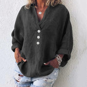 Camicia donna nera in lino con bottoni bianchi, maniche lunghe arrotolate, abbinata a jeans strappati. Stile casual elegante.