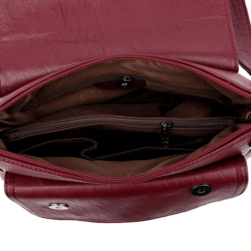 Borsa a tracolla in pelle rossa con scomparti interni, chiusura a bottone e cerniere. Elegante e pratica per uso quotidiano.