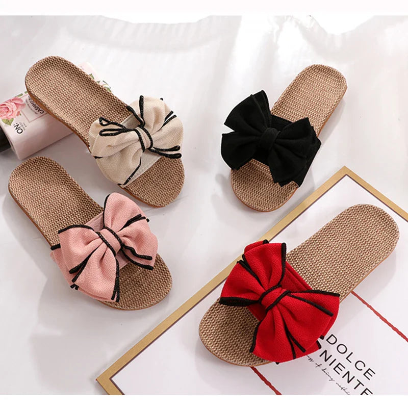 Quattro paia di ciabatte estive in paglia con fiocco, colori beige, nero, rosa e rosso, su sfondo bianco. Scarpe donna moda estiva.