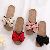 Quattro paia di ciabatte estive in paglia con fiocco colorato: beige, rosa, rosso e nero. Design elegante e comodo per donna.