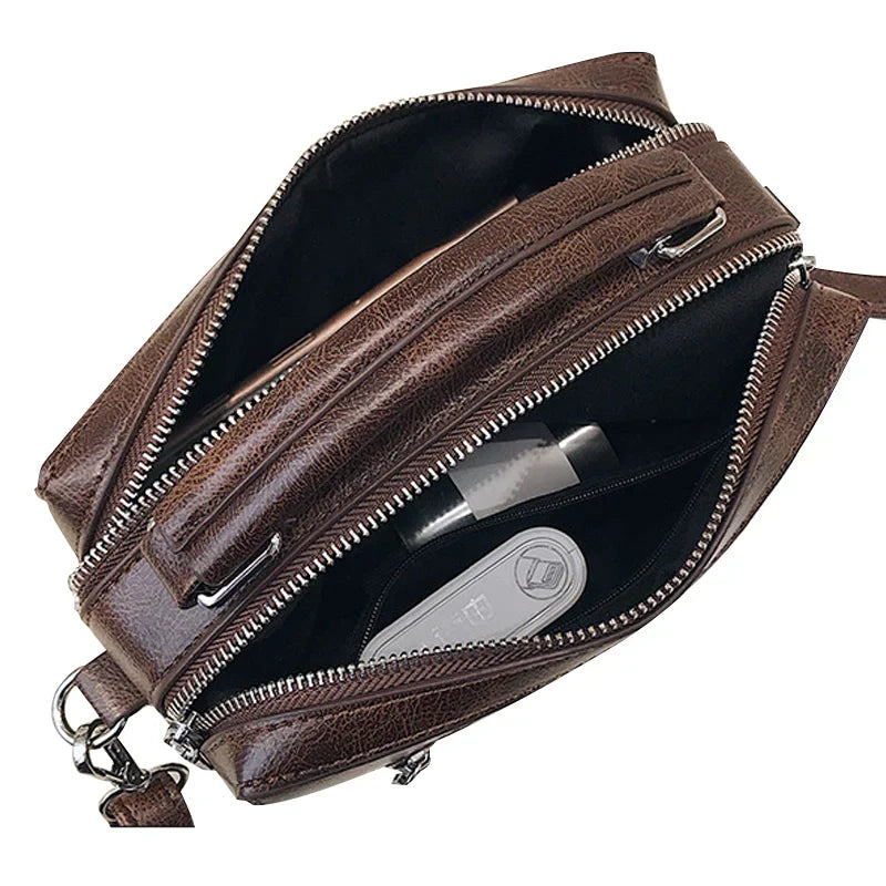 Borsa a tracolla in pelle marrone con cerniere aperte, scomparti multipli e accessori interni. Elegante e pratica per uso quotidiano.