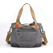 Borsa a tracolla in tela grigia con manici beige, tasca frontale con zip, dettagli in pelle marrone, ideale per moda casual e uso quotidiano.