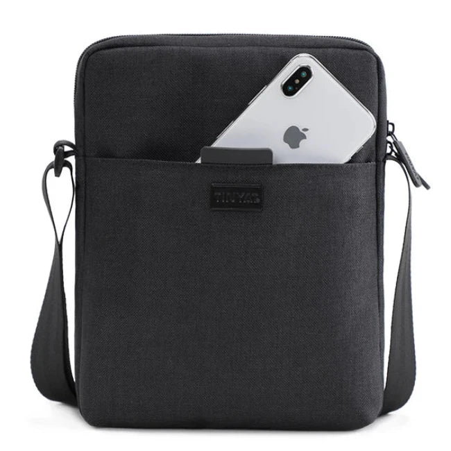 Borsa a tracolla nera in tessuto con tasca frontale contenente uno smartphone. Design moderno, ideale per lavoro e viaggio. Accessorio unisex.