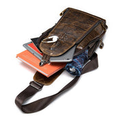Borsa a tracolla in pelle marrone con texture coccodrillo, contenente tablet, libri e ombrello. Design elegante e funzionale per uomo.
