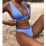 Donna in bikini blu su spiaggia di ciottoli, costume da bagno estivo, moda mare, abbigliamento da spiaggia, relax al sole, tendenza moda 2023.