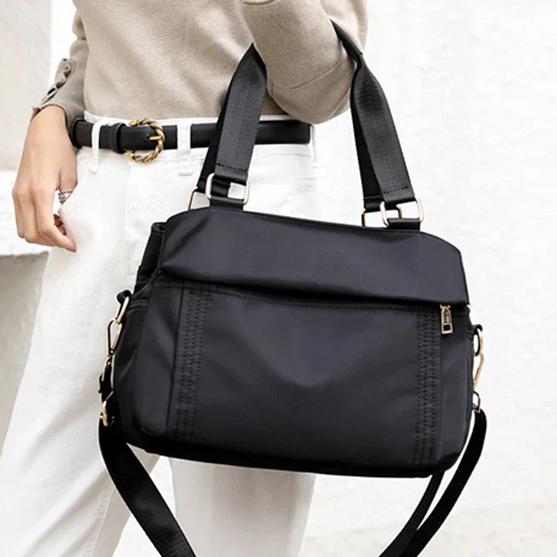 Borsa a tracolla nera elegante, design moderno, con cerniera e manici robusti. Accessorio moda donna, perfetto per uso quotidiano e lavoro.