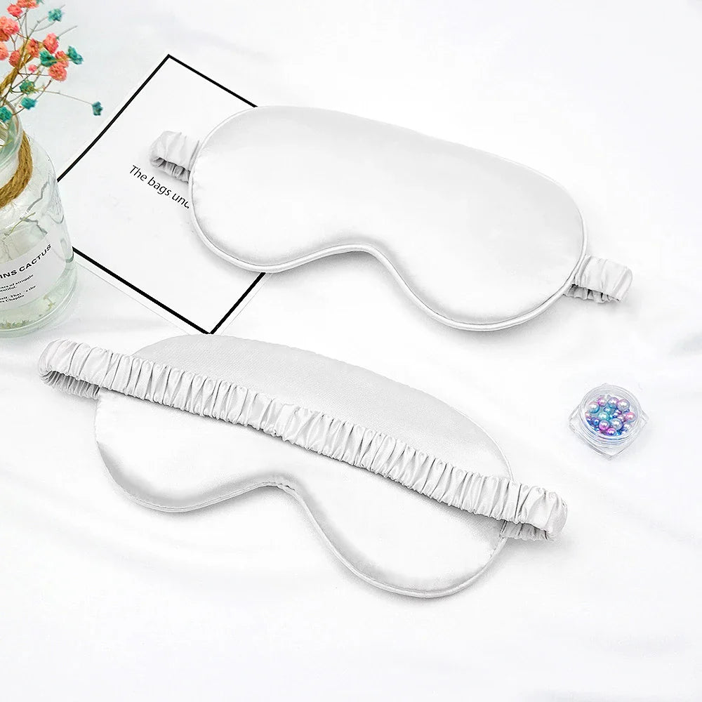Maschera per dormire in seta bianca su sfondo bianco, con elastico regolabile. Accessorio per il sonno, comfort e relax.