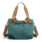 Borsa a tracolla in tela verde con manici beige, dettagli in pelle marrone e tracolla regolabile. Design casual, ideale per uso quotidiano.