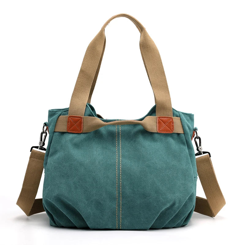 Borsa a tracolla in tela verde con manici beige, dettagli in pelle marrone e tracolla regolabile. Design casual, ideale per uso quotidiano.