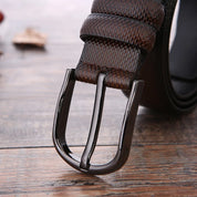 Cintura in pelle marrone con fibbia metallica lucida su sfondo in legno. Accessorio moda uomo elegante, alta qualità, stile classico.