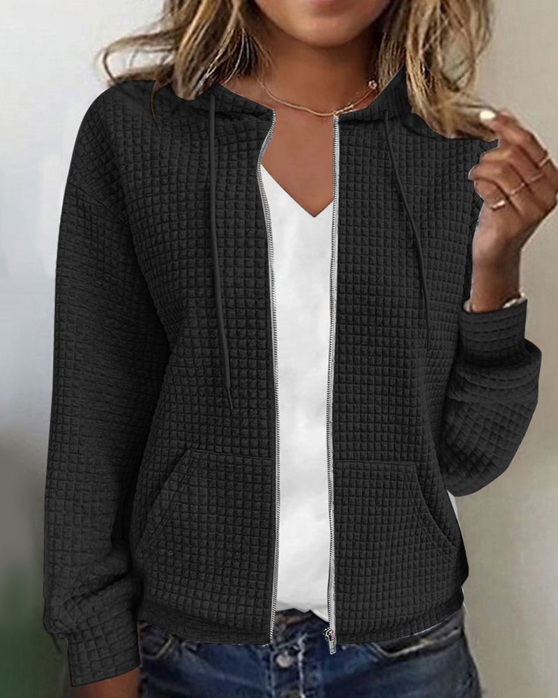 Donna con felpa nera con cappuccio, zip frontale, tasche a marsupio, indossata su maglietta bianca. Stile casual, moda autunnale.