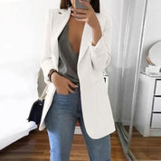 Giacca bianca elegante da donna, abbinata a top grigio scollato e jeans blu. Moda casual chic, outfit primaverile, stile contemporaneo.