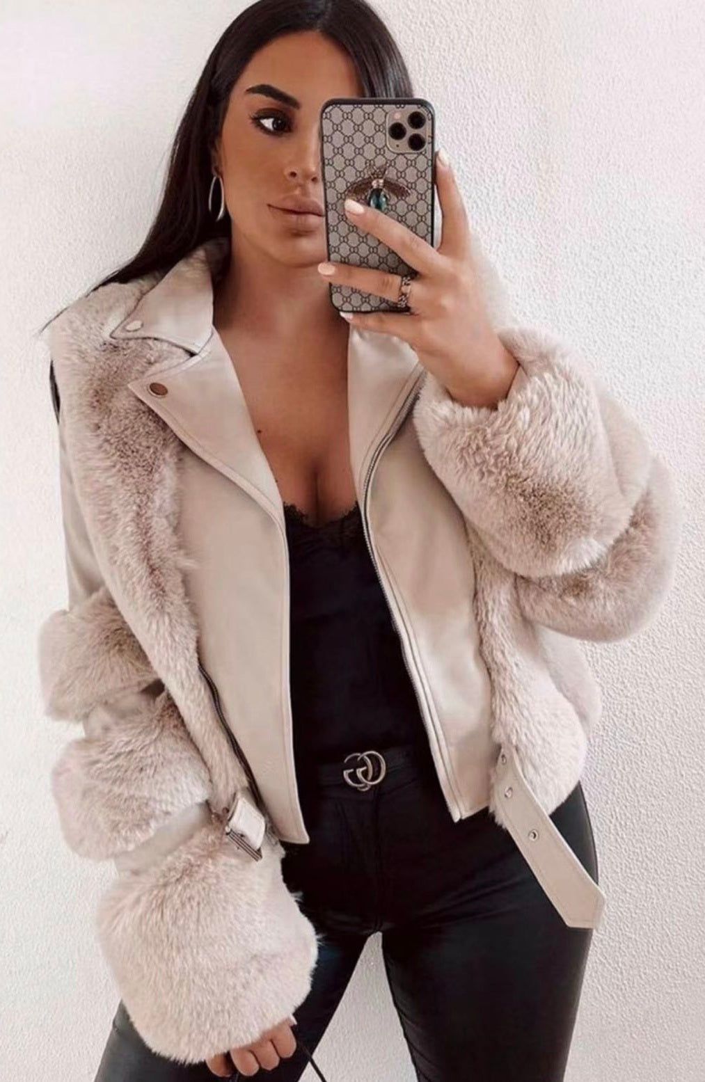 Donna con giacca in ecopelliccia beige, pantaloni neri, top nero, e smartphone. Moda autunno inverno, abbigliamento elegante e trendy.