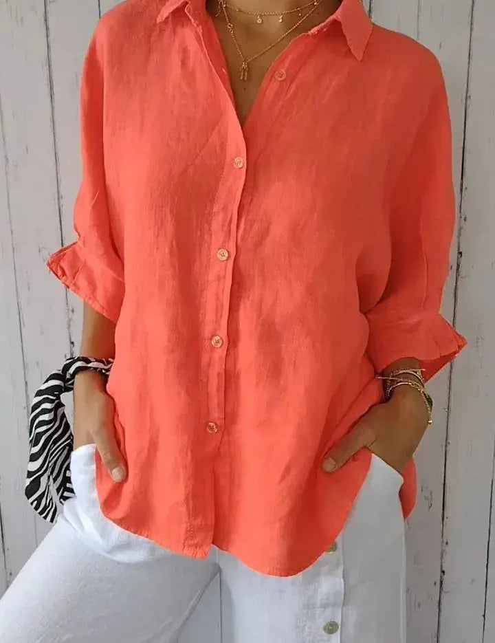 Camicia donna in lino arancione, maniche lunghe, abbinata a pantaloni bianchi. Moda estiva casual, stile elegante e confortevole.
