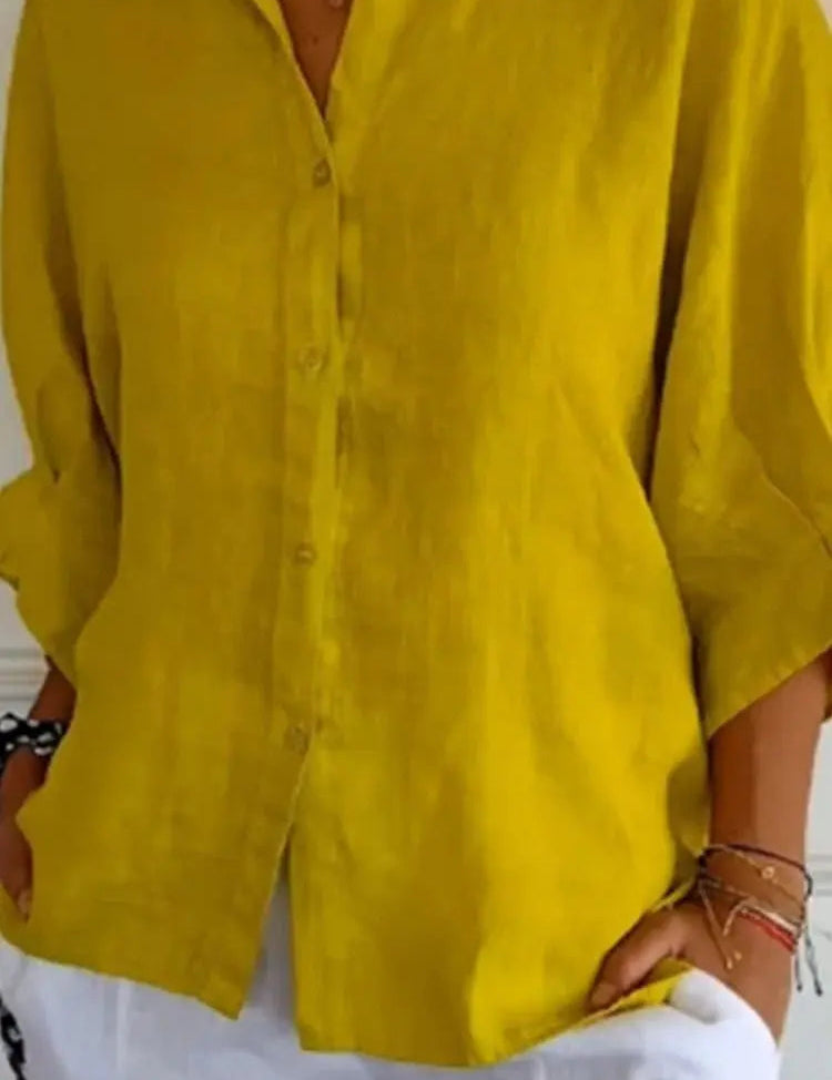 Camicia donna in lino giallo senape, maniche lunghe, abbinata a pantaloni bianchi. Moda estiva casual, abbigliamento leggero e traspirante.