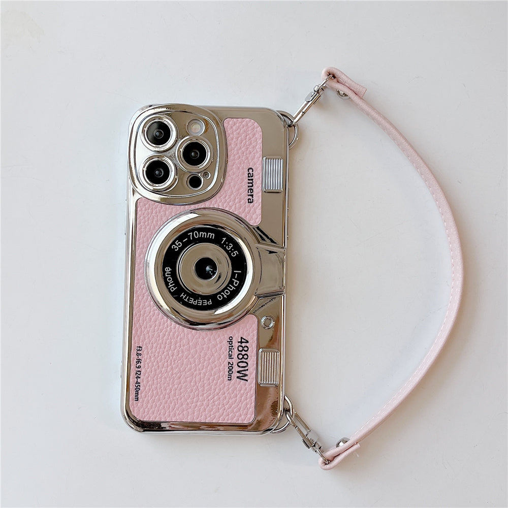 Custodia per iPhone a forma di fotocamera vintage rosa, con dettagli argentati e cinturino. Design unico, accessorio moda per smartphone.