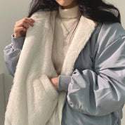 Giacca invernale donna, reversibile, con interno in pelliccia sintetica bianca e esterno grigio, indossata su maglione a collo alto beige.