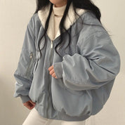 Giacca bomber oversize grigia con zip, colletto in pelliccia sintetica bianca, indossata da una donna. Moda invernale, abbigliamento casual elegante.