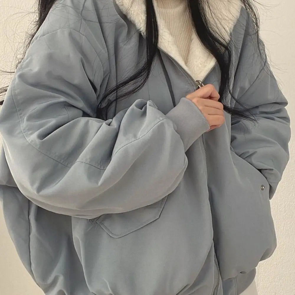 Giacca invernale oversize grigia con zip, colletto in pelliccia sintetica bianca, indossata da una donna. Moda casual, abbigliamento caldo.