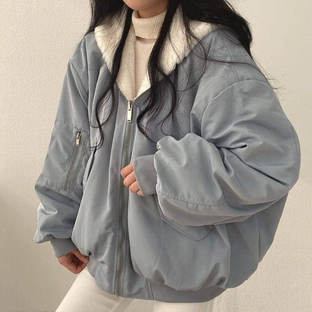 Giacca bomber oversize grigia con zip, colletto in pelliccia sintetica bianca, indossata da una donna. Moda invernale, abbigliamento casual elegante.