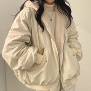 Giacca invernale beige con cappuccio in pelliccia sintetica, indossata sopra un maglione a collo alto. Moda donna, abbigliamento caldo e casual.