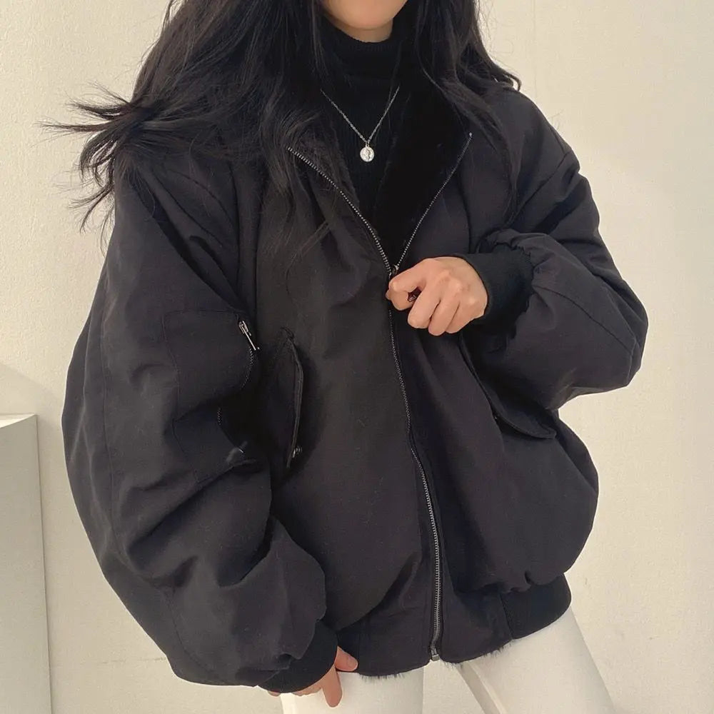 Giacca oversize nera da donna, stile casual, con zip frontale e tasche laterali, indossata su maglione nero. Moda autunnale, abbigliamento femminile.