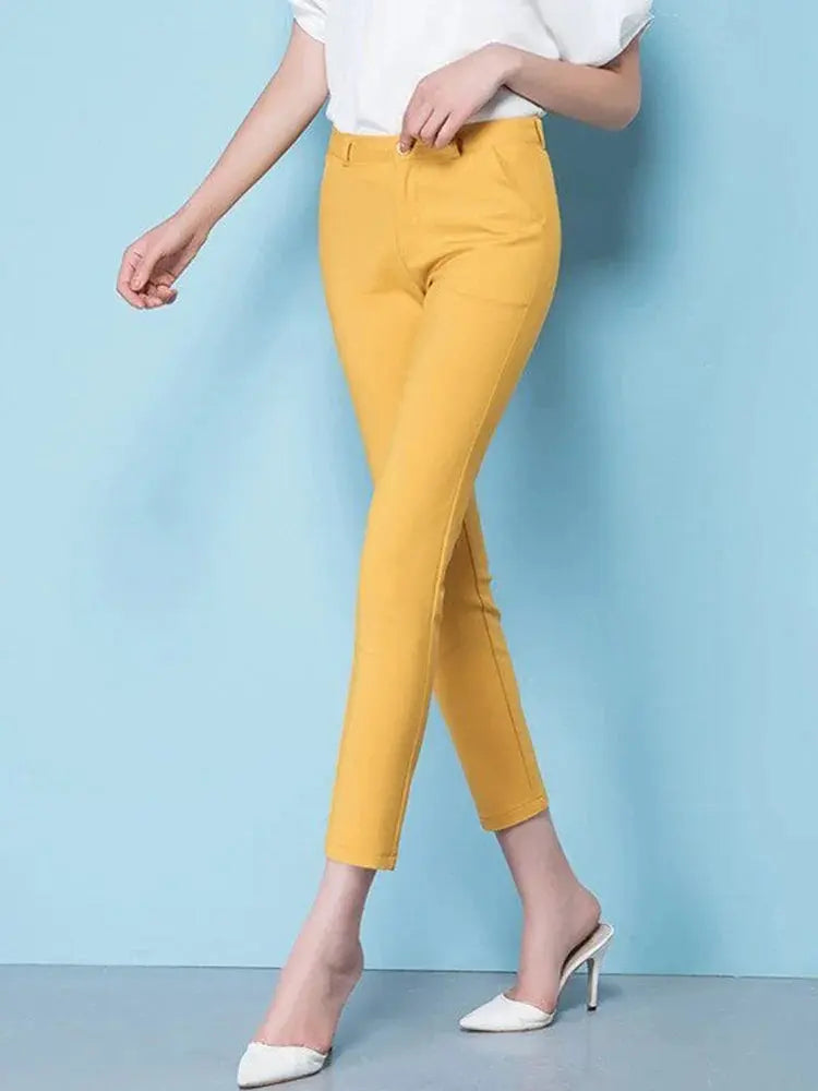 Pantaloni gialli da donna, eleganti e aderenti, abbinati a scarpe bianche con tacco. Ideali per look casual e formali.