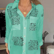 Camicia verde acqua con scritte nere, colletto classico e bottoni frontali. Moda donna, abbigliamento casual elegante, tendenza 2023.