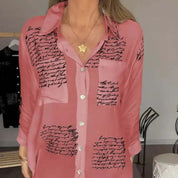 Camicia donna rosa con scritte nere, maniche lunghe, colletto classico, bottoni frontali, stile casual elegante, perfetta per moda autunnale.