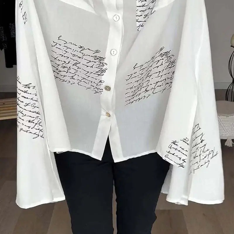 Camicia bianca trasparente con scritte nere, maniche ampie, abbottonatura frontale, stile elegante e moderno, perfetta per moda femminile casual.