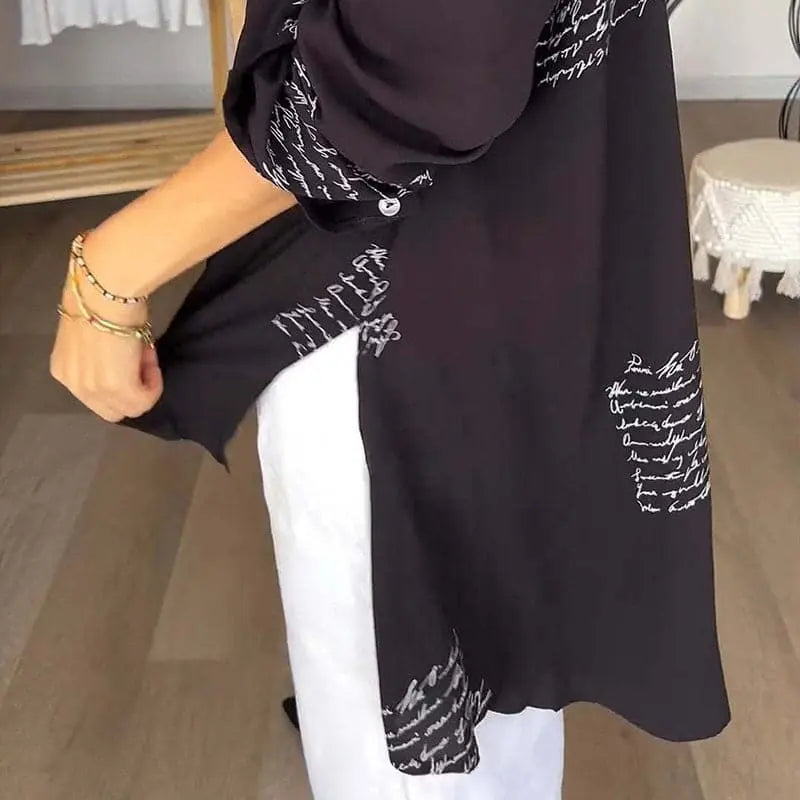 Camicia nera con scritte bianche, maniche lunghe, abbinata a pantaloni bianchi. Moda casual donna, tessuto leggero, stile elegante.