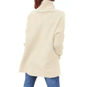 Maglione donna beige a collo alto, maniche lunghe, in maglia morbida, abbinato a jeans blu. Moda autunno inverno, abbigliamento casual elegante.