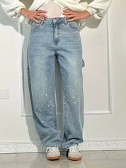 Jeans a gamba larga in denim chiaro con dettagli glitterati, indossati con sneakers bianche. Moda casual, stile trendy, abbigliamento femminile.