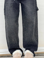 Jeans neri con strass scintillanti, design moderno, vestibilità comoda, abbinati a stivali beige in pelliccia sintetica.