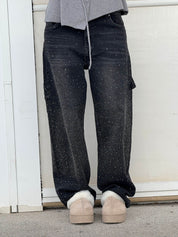 Jeans neri con dettagli glitterati, indossati con scarpe beige invernali. Moda casual, pantaloni decorati, stile urbano.