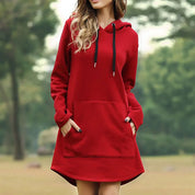 Donna con felpa rossa con cappuccio, tasche frontali, in un parco verde. Abbigliamento casual autunnale, moda femminile, stile confortevole.