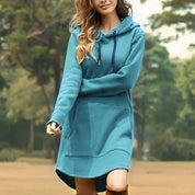 Donna con abito felpa con cappuccio blu, tasca frontale, in un parco. Moda casual autunnale, abbigliamento comodo, stile urbano.