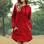 Donna con felpa rossa con cappuccio, tasca frontale e lacci neri, in un parco. Abbigliamento casual autunnale, moda donna, stile confortevole.