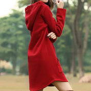 Donna con abito rosso con cappuccio in un parco verde. Moda autunnale, vestito casual, abbigliamento femminile elegante.