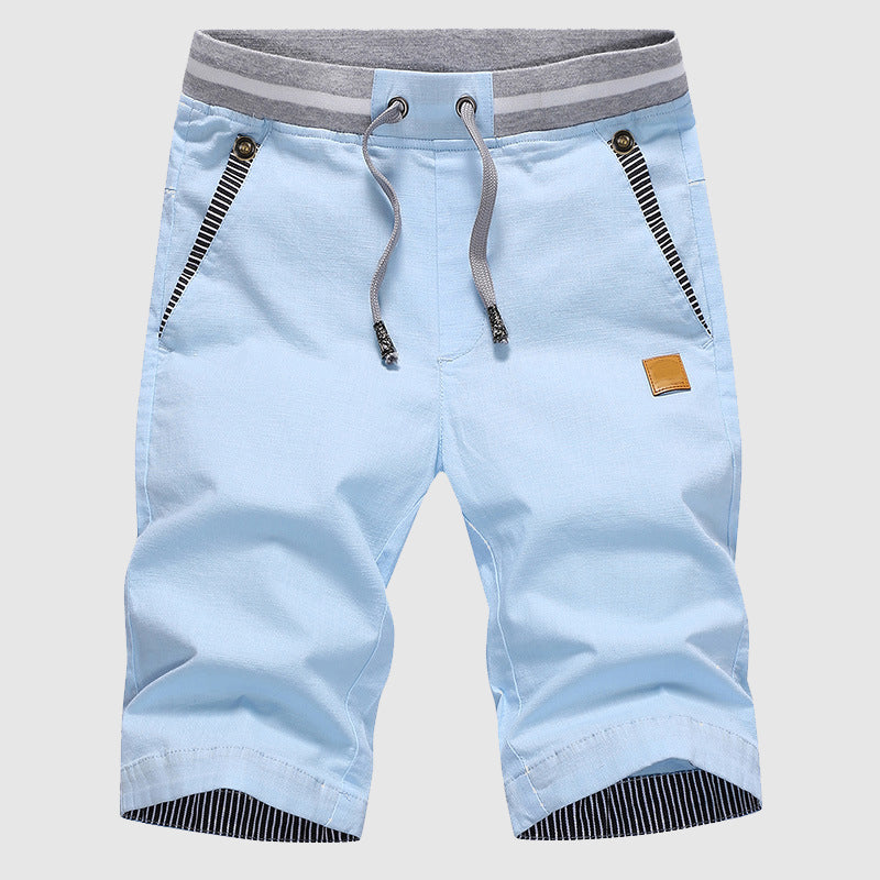 Pantaloncini uomo azzurri con coulisse, tasche con zip, dettagli a righe grigie, ideale per moda estiva casual. Tessuto leggero e confortevole.