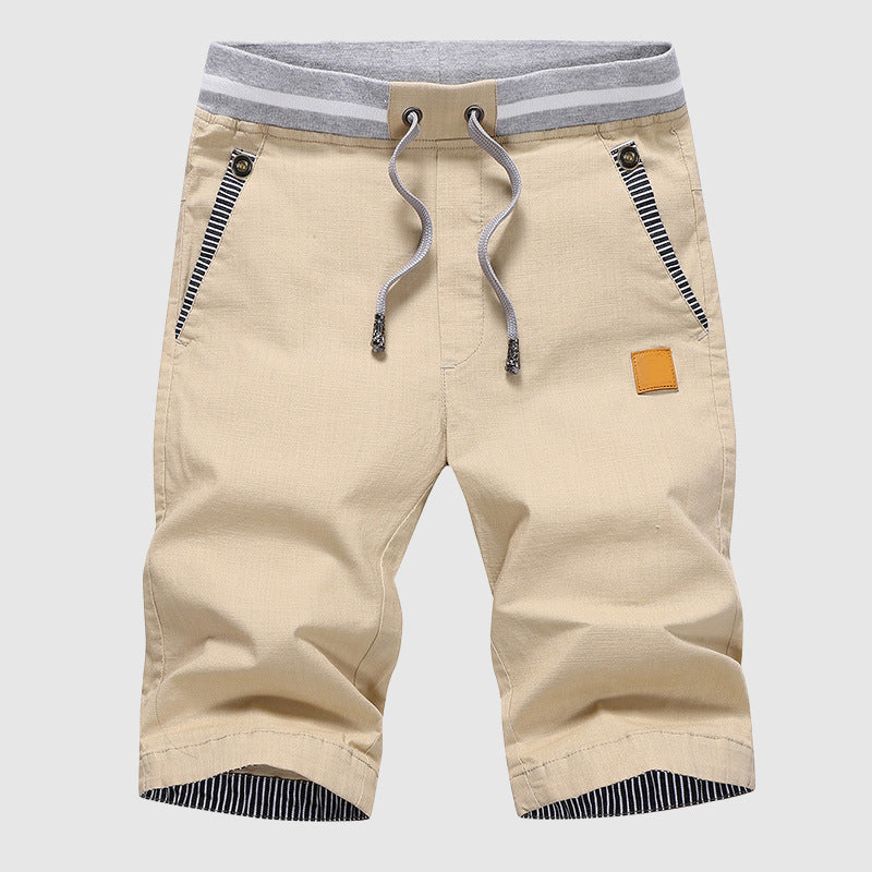 Pantaloncini beige da uomo con coulisse, tasche con zip e dettagli a righe. Design casual, ideale per l'estate. Moda maschile, abbigliamento estivo.