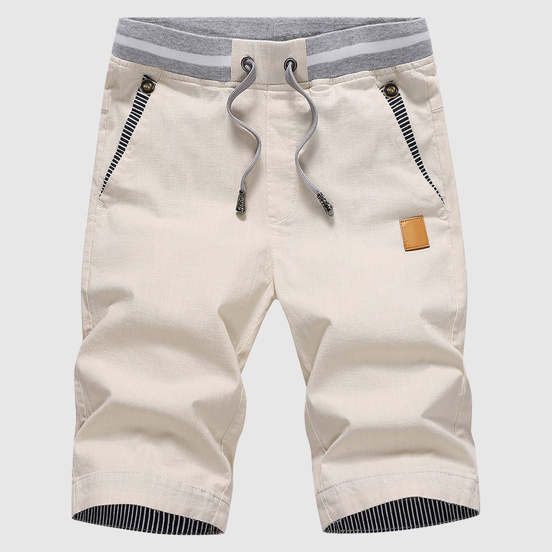 Pantaloncini beige da uomo con coulisse, tasche con zip, dettagli a righe grigie, ideali per moda estiva casual. Tessuto leggero e confortevole.