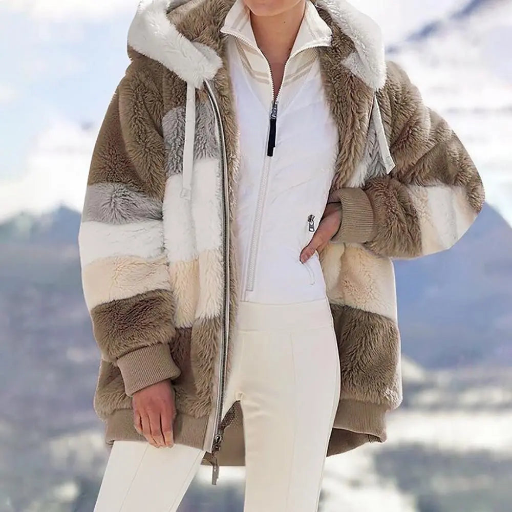 Giacca invernale donna in pelliccia sintetica a righe beige e bianche, con cappuccio, indossata su montagna innevata. Moda inverno, abbigliamento caldo.